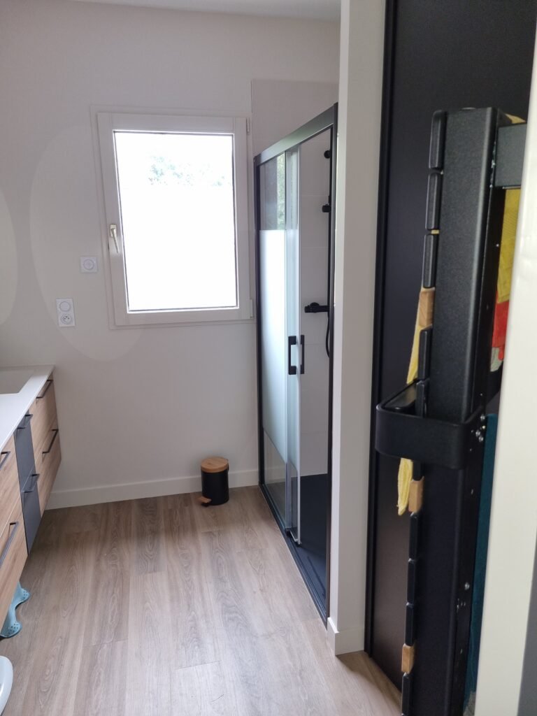 Douche vitrée et sèche-serviettes noir dans une salle de bain rénovée à Rennes